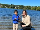 Smiling with a tiger grin, Dev was waiting to put his bark boat into Spy Pond with his mother, Cheryl, kneeling at his side.